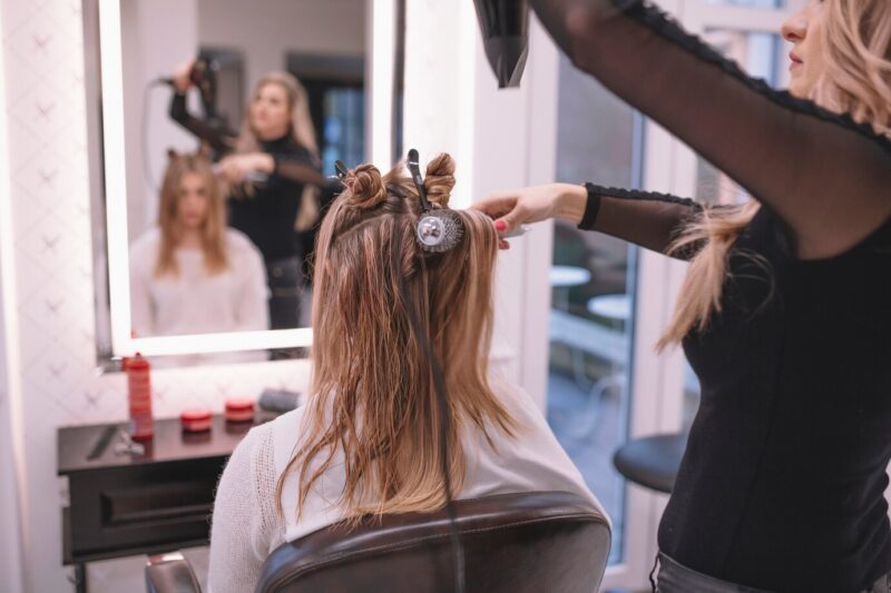 hairstylist is drying a woman's hair