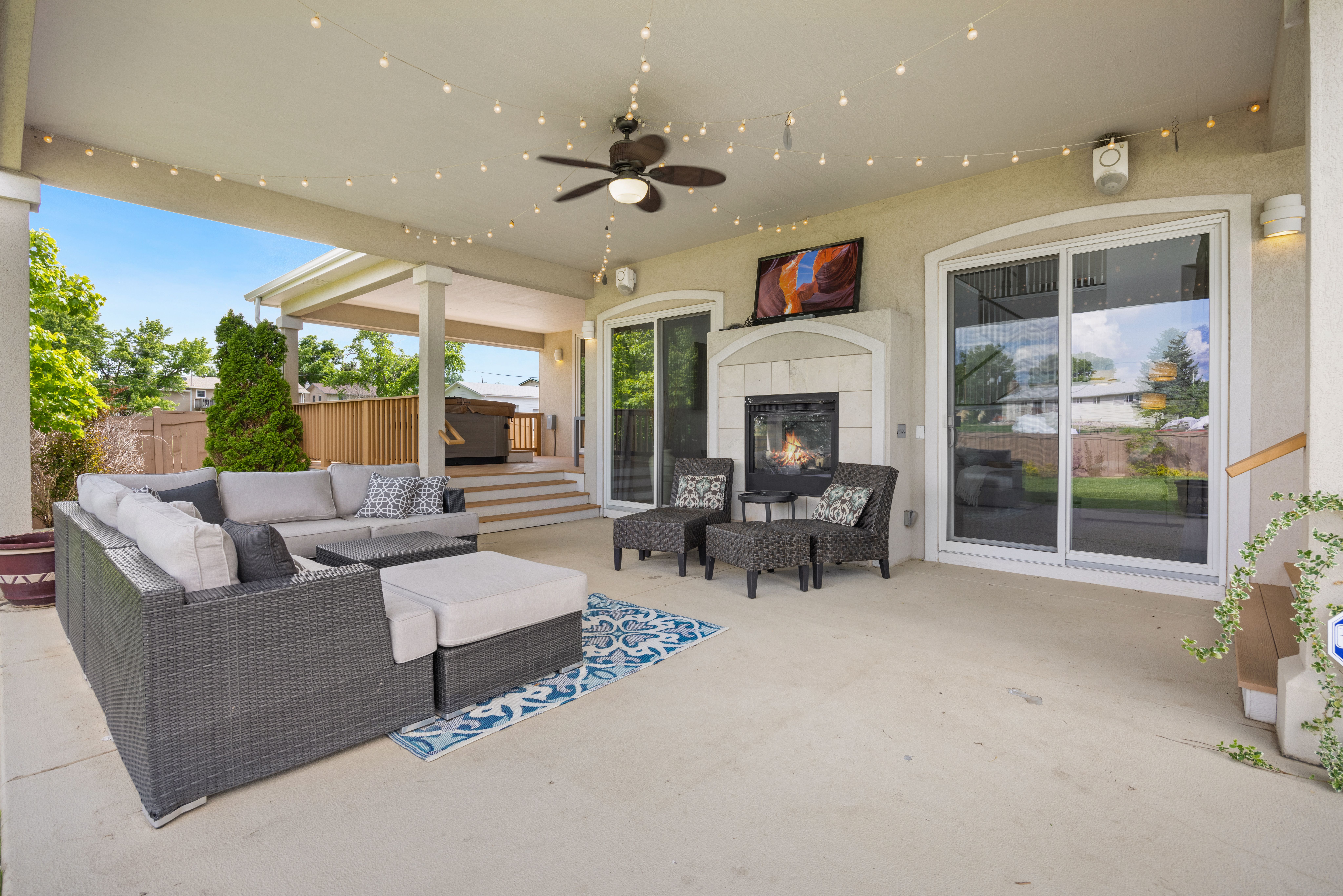 Luxury outdoor patio with comfortable seating, fireplace, and ambient string lights