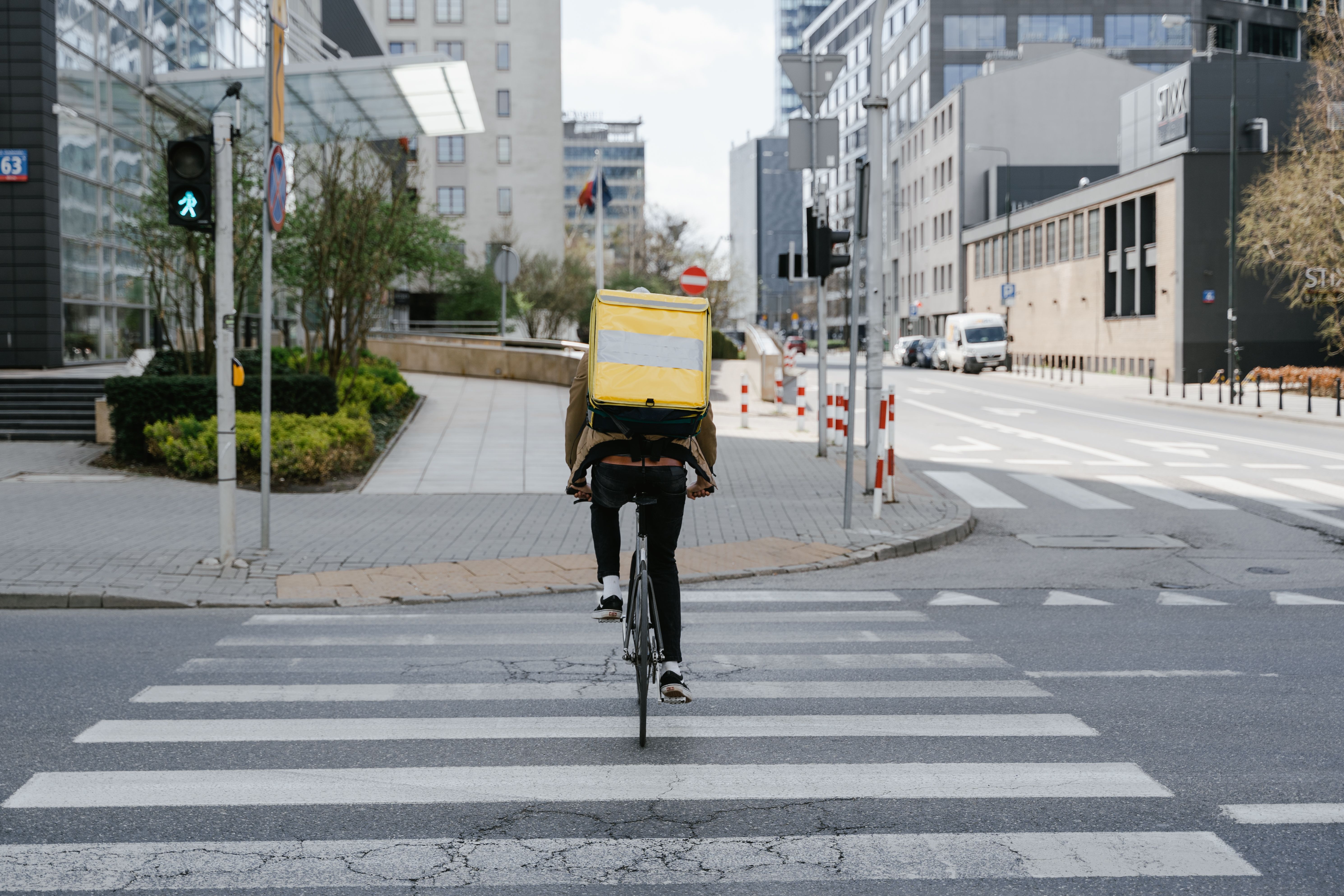 Bicycle courier carrying a thermal delivery bag through a downtown street